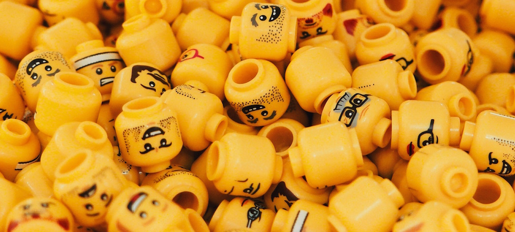 A pile of lego heads with different emotions and expressions