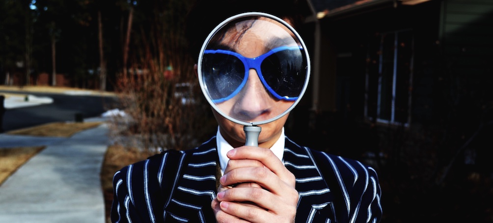 Person holding magnifying glass up to face