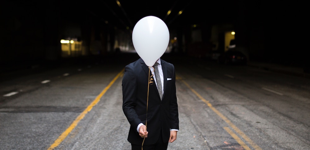 Man in suit with a balloon in front of his face