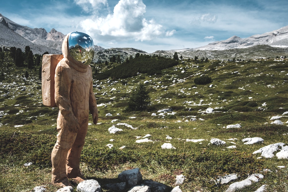 A wooden astronaut standing in the Alps