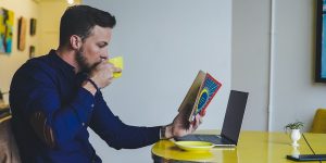 A man sips on coffee while reading a book