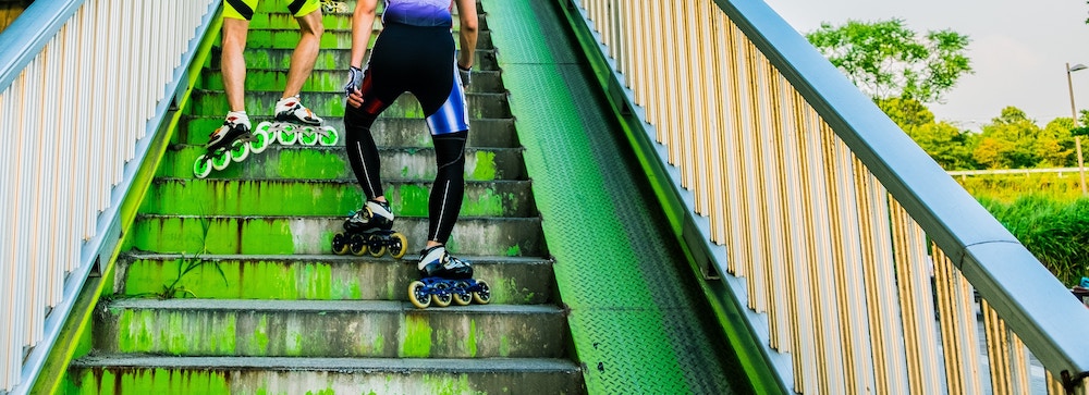 Two roller bladers tramp up a metal staircase