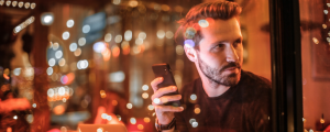 customer experience digital experience man holding mobile phone in a cafe